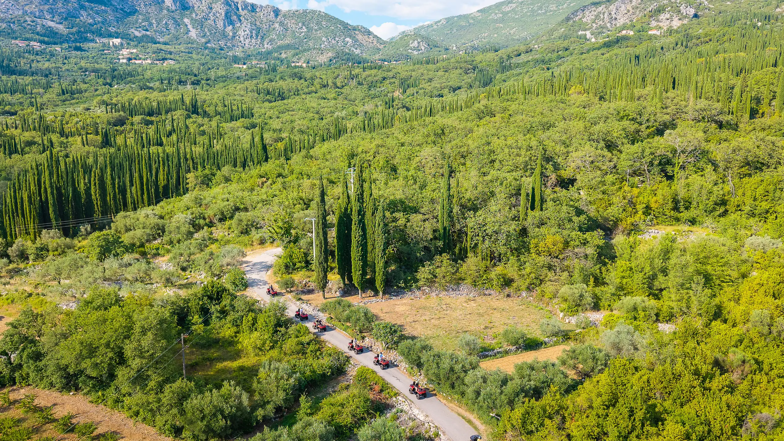 Zračna panorama Konavoskog polja s vijugavom cestom i konvojem quadova